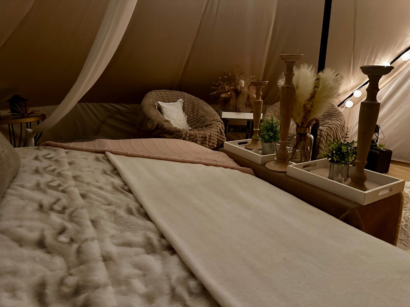Side view of a styled bell tent bed with canopy drape, tray styling and elegant neutral linens.